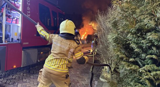 Bouwcontainer in lichterlaaie naast schutting in Leeuwarden